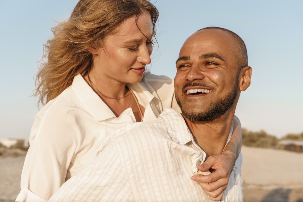 Young happy couple on seashore enjoying the sea